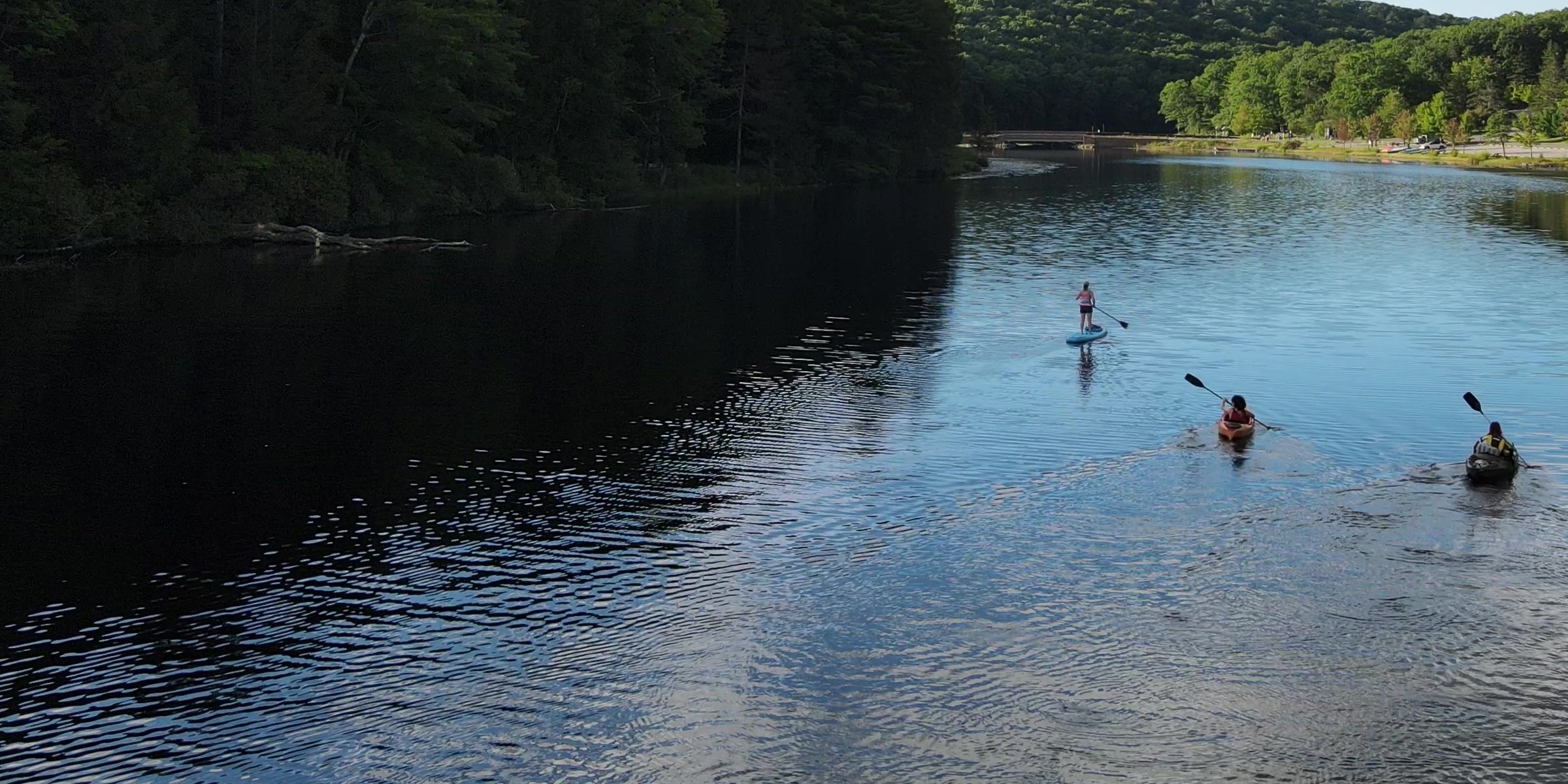 A paddle boarder and two kayakers on Black Moshannon Lake — drone view, Black Moshannon State Park near Julian, Pennsylvania